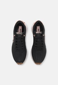 Svarta sportskor med en smidig design, övre del i tyg, rosa detaljer, runda snören och en brun gummisula för bra grepp.