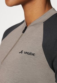 Grå og mørkegrå zip-up genser laget av myk stoff med rund krage og frontglidelås, med "VAUDE" logoen på brystet.
