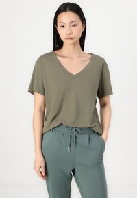 Olive green V-neck t-shirt in soft fabric with short sleeves, paired with drawstring waist pants in a matching muted green tone.