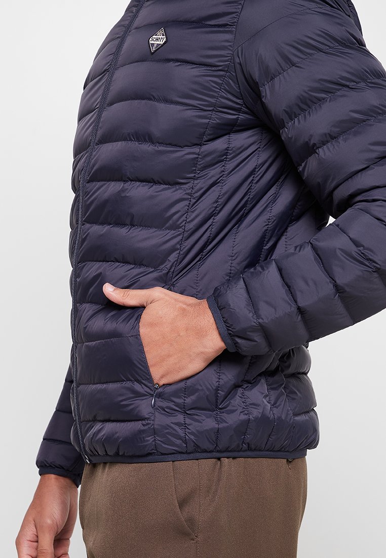Marineblaues Steppjacke mit horizontalen Quiltabschnitten, einem durchgehenden Reißverschluss und seitlichen Taschen, hergestellt aus einem leichten, weichen Material.