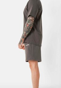 Grijze katoenen T-shirt en bijpassende shorts, met een relaxte pasvorm, ronde hals en logo-detail op de shorts. Zachte textuur, minimalistisch ontwerp.