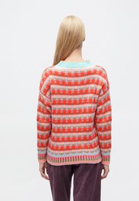 Pulover tricotat cu un model floral și dungi în nuanțe de roșu, roz și albastru deschis. Mâneci și tiv cu reiat. Croială lejeră, cu decolteu rotund.