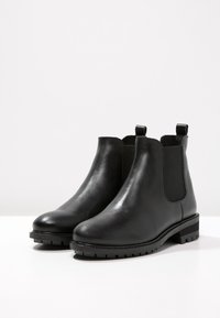 Czarne skórzane botki za kostkę z elastycznymi panelami bocznymi, okrągłym noskiem i teksturowaną gumową podeszwą. Posiadają uchwyty do łatwego zakładania.