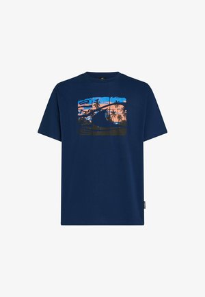 T-shirt in cotone blu navy con una grafica di palme e un tramonto in tonalità arancioni e blu. Maniche corte e scollo rotondo.