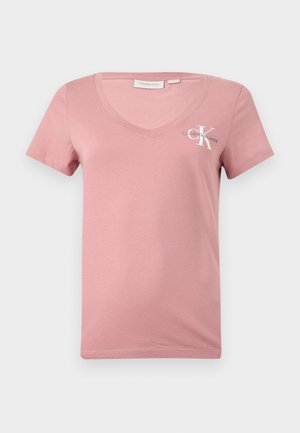 Rosa Baumwoll-V-Ausschnitt-T-Shirt mit kurzen Ärmeln, das ein weißes Calvin Klein-Logo und den Buchstaben "K" auf der linken Brustseite zeigt. Glatte Textur.