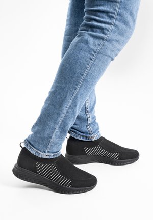 Black athletic shoes made of mesh material with a textured upper and rubber sole. Featuring white stripes across the sides.
