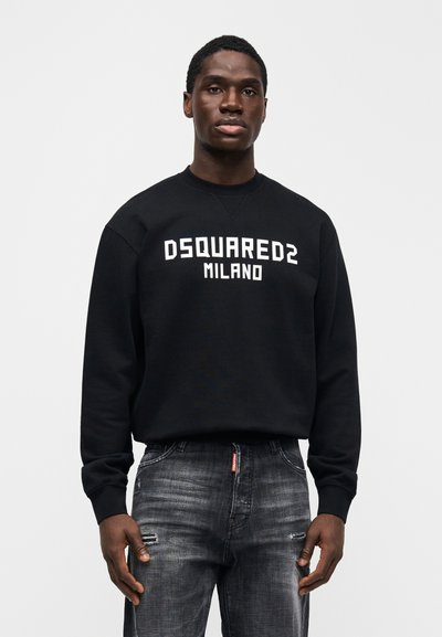 Schwarzer Sweatshirt mit "DSQUARED2 MILANO" in fettem weißem Text, kombiniert mit abgenutzten grauen Jeans. Mit rundem Ausschnitt und langen Ärmeln.