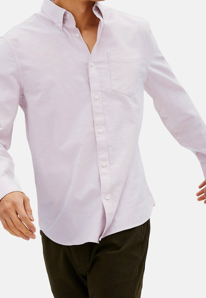 Camicia button-up rosa chiaro con colletto, maniche lunghe e taschino sul petto, realizzata in un tessuto morbido con una texture liscia.