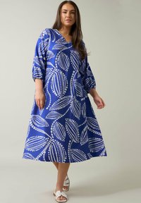 Vestido azul con estampado de hojas blancas, escote en V y mangas hasta los codos. Corte en A fluido con tejido texturizado, adecuado para un uso casual.