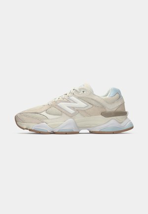 Baskets de sport en mesh et suède beige et bleu clair avec un logo "N" blanc et une semelle épaisse blanche et marron, vue de côté.