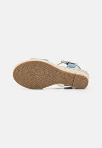 Sandale bleue à talon en wedge avec semelle en liège, semelle extérieure en caoutchouc texturé et accent de boucle métallique. Dispose d'une sangle à la cheville élégante et d'un design respirant.