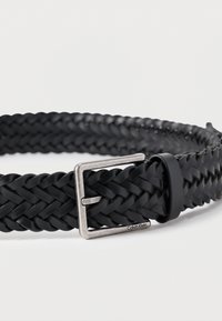 Μαύρη πλεκτή δερμάτινη ζώνη με ασημένια ορθογώνια αγκράφα και μαύρο κρίκο. Διακριτικό λογότυπο της μάρκας εμφανές στη ζώνη.