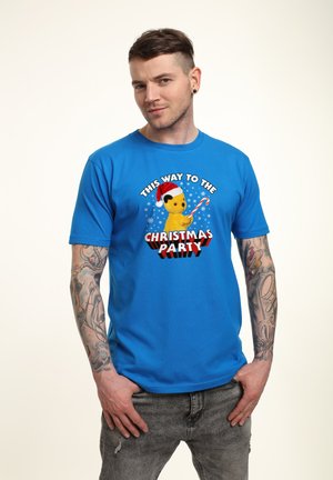 Blå bomulds t-shirt med en gul tegneseriefigur iført en julesok, der holder et slikstok med teksten "DENNE VEJ ER TIL JULEFESTEN."