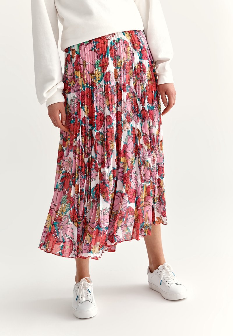 Gonna midi plissettata bianca con un vivace motivo floreale rosa e rosso. Indossata con sneakers bianche, realizzata in un tessuto morbido e leggero.