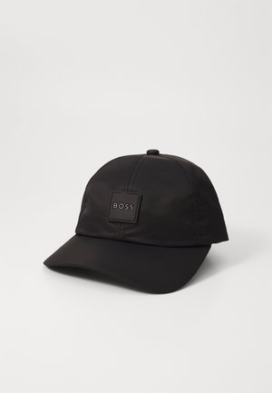 Sort baseballkasket med buet skygge og et firkantet mærke foran med ordet "BOSS" i hvide bogstaver.