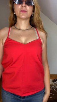 Red sleeveless top with adjustable spaghetti straps, smooth texture, V-neck design, and central seam detail, paired with light-wash denim jeans.