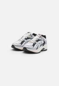 Scarpe da corsa nere e argento con tessuto in rete, punta arrotondata e suola testurizzata. Presentano lacci beige e finiture argento sui lati.