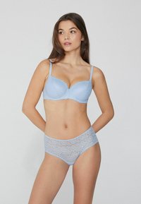 Sujetador de encaje azul claro con bordes ondulados y braguitas de encaje de talle alto a juego, que presentan patrones florales y una textura suave.