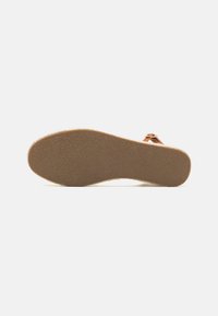 Brown rubber sandal sole with textured surface; features a single strap and a slight curve at the toe for ergonomic design.