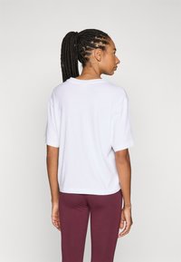 White cotton t-shirt with a relaxed fit, short sleeves, and a slight drop shoulder. Features a round neckline and a straight hemline.