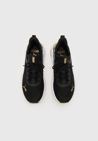 Chaussures de sport noires avec un dessus en mesh, un collier rembourré et un système de laçage. Présente des accents dorés et une semelle blanche. Marquage notable sur la languette.