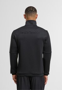 Černá, lehká bunda s vysokým límcem, dlouhými rukávy a vyraženým logem "Sergio Tacchini" na zadní straně. Hladká textura, atletický střih.