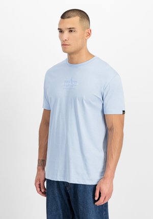 T-shirt in cotone azzurro chiaro con scollo rotondo, maniche corte e stampa grafica frontale. Presenta un'etichetta nera sulla manica sinistra.