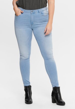Light blue skinny jeans with a smooth texture, mid-rise waist, front pockets, and minimal fading, paired with black ankle boots.