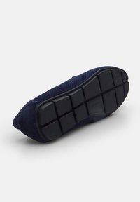 Navy suede jalan yang memiliki sol tekstur, bawah karet dengan pola grid untuk traksi; sisi dilengkapi dengan perforasi kecil untuk sirkulasi udara.