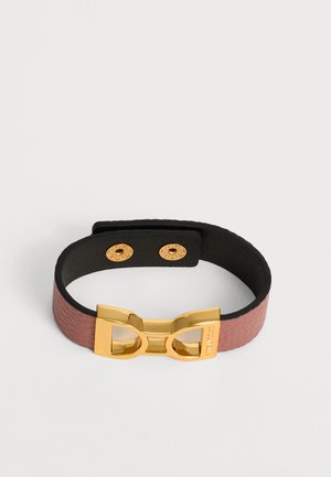 Pulsera ancha de cuero rosa con hebilla geométrica en tono dorado y dos broches dorados, mostrada sobre un fondo blanco liso.