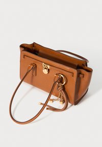 Bruine leren handtas met gouden hardware, textuur oppervlak, dubbele handvatten en decoratieve kettingaccenten. Open ontwerp toont een ruime binnenkant.