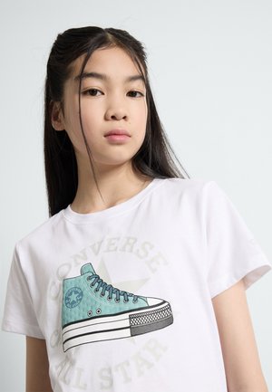 T-shirt blanc avec un graphisme d'une sneaker Converse teal avec des lacets noirs et une semelle à motifs, accompagnée du texte "Converse All Star".