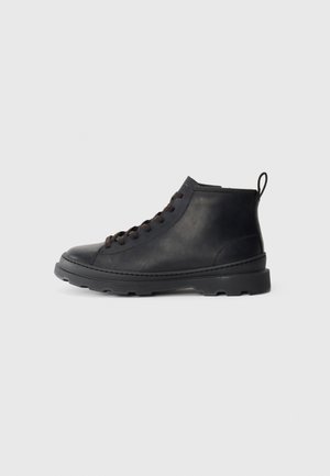 Black leather ankle boots with a smooth texture, round toe, black laces, and a thick rubber sole featuring lug traction patterns.