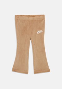 Hnedé zamatové rozšírené legíny s jemnou textúrou a vyšitým bielym logom Nike na boku. Žiadne vrecká ani ďalšie ozdoby nie sú viditeľné.