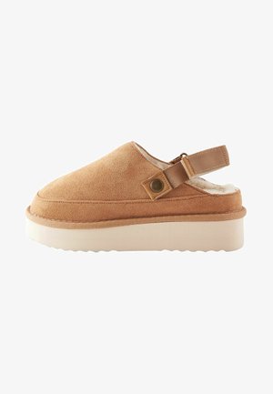 Barna velúr klumpák zárt orral, állítható hátsó pánttal és puha fehér béléssel. Lekerekített talp és textúrált gumitalp.