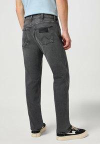 Jeans gris oscuro con corte recto, que presentan bolsillos traseros y un parche de cuero. El denim texturizado ofrece un aspecto casual.