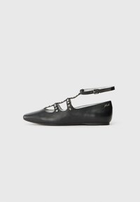 Zapatos planos de cuero negro con punta afilada, que presentan un diseño con recortes, acentos de tachuelas y una correa ajustable en el tobillo. Textura suave, patrón minimalista.