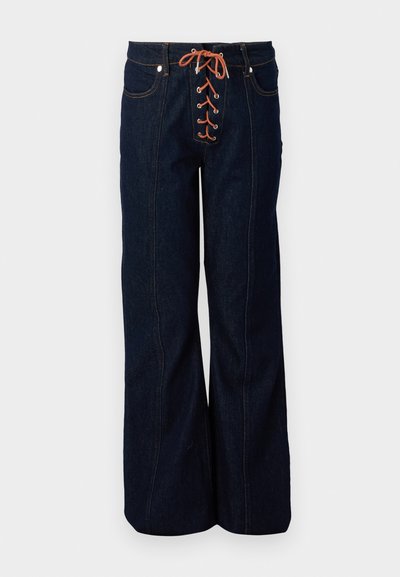 Pantalones de mezclilla oscuros de talle alto con pierna acampanada, que presentan un frente decorativo con cordones, cordones naranjas y costuras contrastantes.