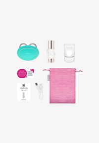 L'ensemble de dispositifs de soin de la peau Foreo comprend un appareil turquoise, un sérum dans un flacon transparent, une pochette de rangement rose, un câble USB et des cartes d'information.