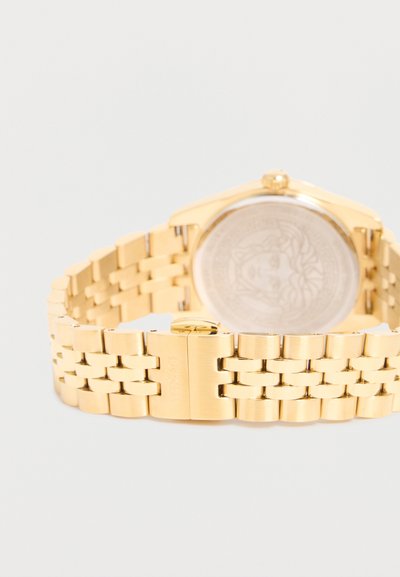 Χρυστό μεταλλικό μπρασελέ ρολογιού με κούμπωμα και μερικώς ορατό χαραγμένο πίσω μέρος ρολογιού που δείχνει σχεδιασμό κεφαλής Μέδουσας.