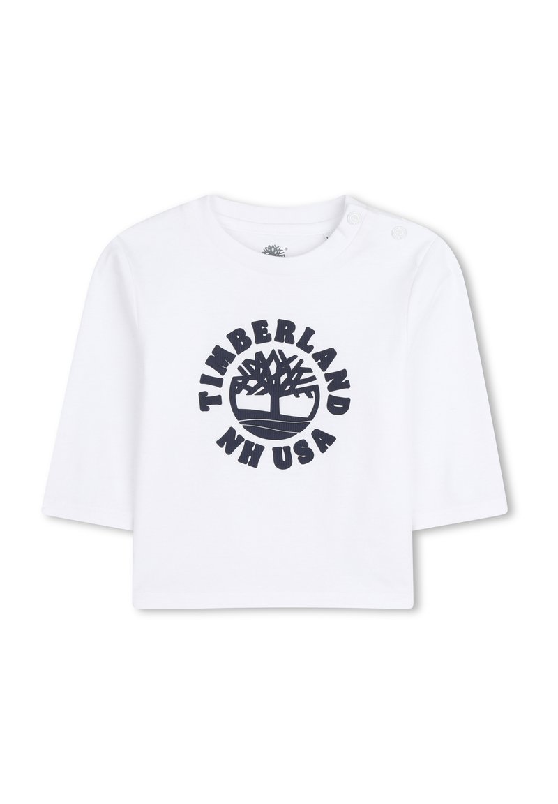 Witte katoenen overhemd met korte mouwen, voorzien van een marineblauw, rond Timberland-logo met een boomafbeelding en de tekst "NH USA." Twee drukknopen op de schouders.