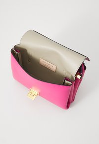 Pink leather handbag with smooth texture, flap closure, and gold hardware. Interior features a beige lining and brand label.