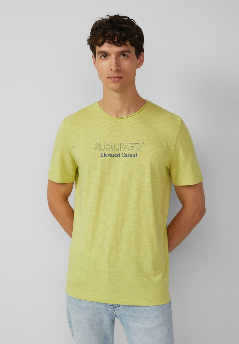 Jasnożółta koszulka z krótkim rękawem i okrągłym dekoltem. Zadrukowana napisem "S. OLIVER" oraz "Elevated Casual" w ciemnoniebieskim kolorze. Miękka w dotyku.