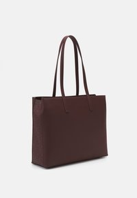 Burgunderfärgad tote-väska med dubbla handtag, slät textur, rektangulär form och präglat logomönster på ena sidan. Dragkedjestängning upptill.