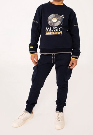 Completo della felpa e pantaloni della tuta di colore blu navy con una grafica di un disco in vinile e il testo "CONCERTO MUSICALE", realizzato in tessuto morbido con dettagli a costine.