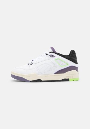 Baskets blanches avec des accents violets et noirs, tige en cuir, semelle texturée et détail vert au niveau du talon. Comprend des lacets et une ventilation sur les côtés.