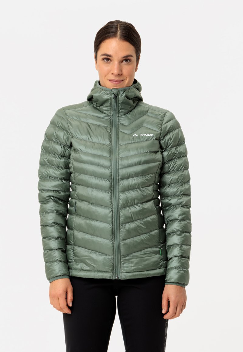 Groene synthetische pufferjack met verticale stiksels, hoge kraag, ritssluiting aan de voorkant en logodetail op de linkerkant van de borst. Glad, glanzend textuur.