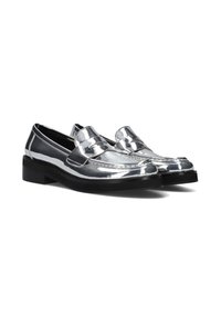 Metallische zilveren loafers met een glanzende afwerking, zwarte zool en decoratieve strikdetail aan de voorkant; gestikte accenten langs de randen.