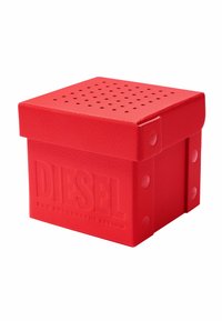 Rote Aufbewahrungsbox aus strukturiertem Material mit einem gelochten Deckel und eingeprägtem "DIESEL"-Logo auf der Vorderseite. Quadratische Form mit abgerundeten Kanten.