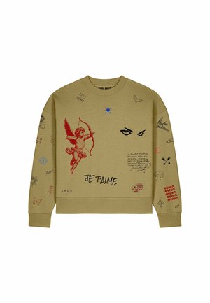 Béžová mikina s červeným cherubínom, ktorý mieri lukom, čierne oči, text „Je T'aime“ a rôzne malé symboly ako motýle, kocky, vtáky a ručne písaný text.